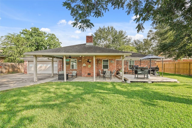 rear view of house featuring a lawn, ceiling fan, a garage, and a deck