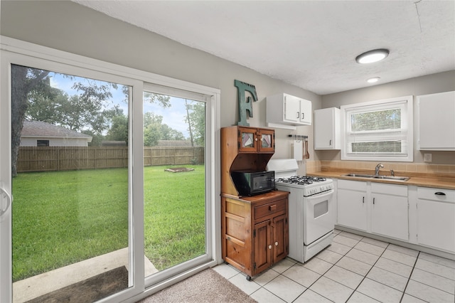 kitchen with white cabinetry, white gas stove, sink, a textured ceiling, and light tile patterned floors