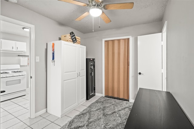 kitchen featuring white range oven, ceiling fan, white cabinets, and light tile patterned floors