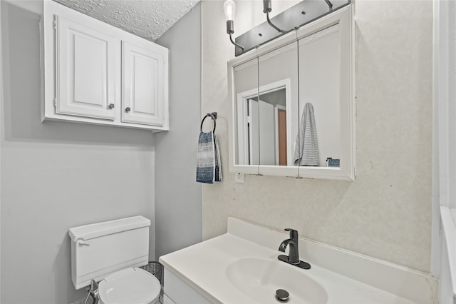 bathroom featuring vanity, a textured ceiling, and toilet