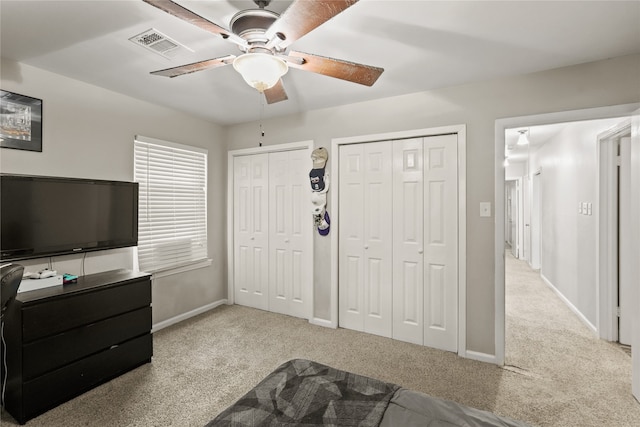 carpeted bedroom featuring two closets and ceiling fan