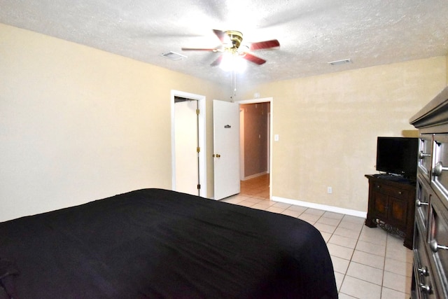 unfurnished bedroom featuring a textured ceiling, light tile patterned flooring, and ceiling fan