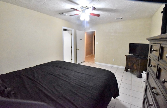 bedroom featuring ceiling fan, light tile patterned floors, and a textured ceiling