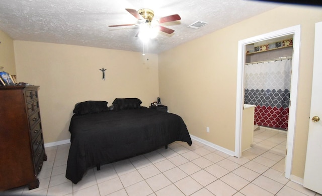 tiled bedroom with ceiling fan and a textured ceiling