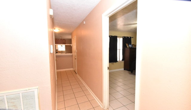 hall featuring a textured ceiling and light tile patterned floors