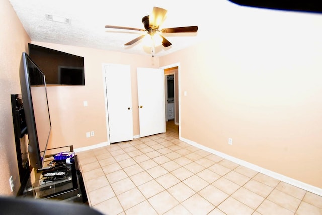 interior space with ceiling fan, light tile patterned floors, and a textured ceiling