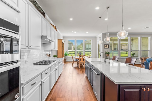 kitchen with sink, light hardwood / wood-style flooring, a center island with sink, white cabinetry, and stainless steel appliances