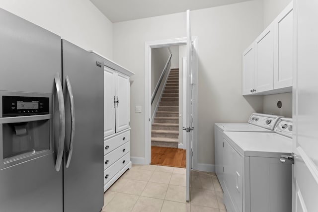 laundry area featuring washer and clothes dryer, light tile patterned flooring, and cabinets