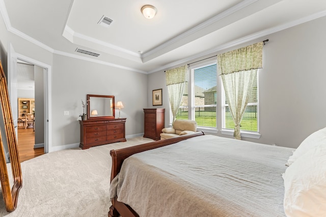 bedroom featuring light wood-type flooring, ornamental molding, and a tray ceiling