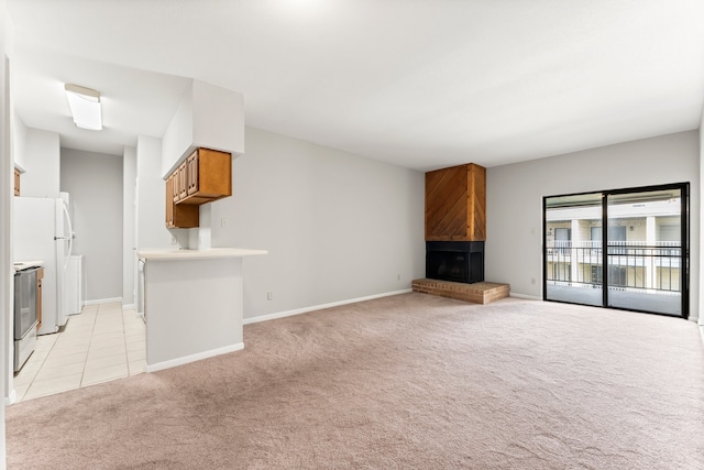 unfurnished living room with light carpet and a brick fireplace