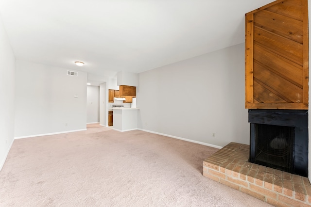 unfurnished living room featuring light carpet and a brick fireplace