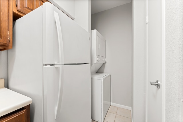 laundry area with light tile patterned floors and stacked washer / drying machine