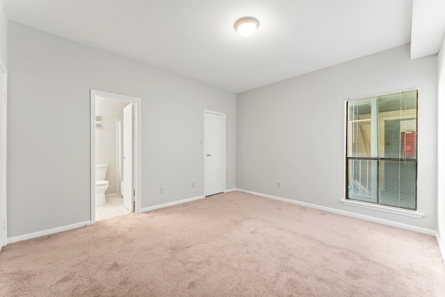 unfurnished bedroom featuring light carpet, connected bathroom, and a closet