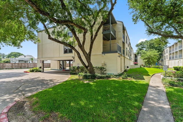 view of front facade featuring a carport, a balcony, and a front lawn