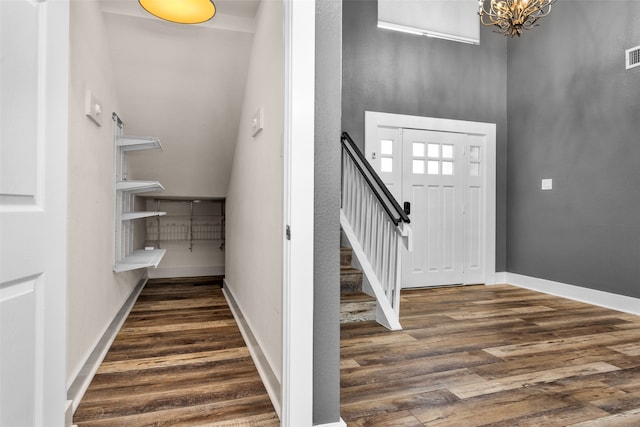 entryway featuring an inviting chandelier, vaulted ceiling, and dark hardwood / wood-style floors