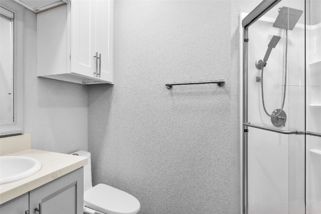 bathroom with a shower with door, vanity, and toilet