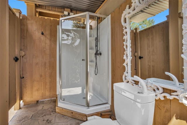 bathroom featuring wooden walls, toilet, and an enclosed shower