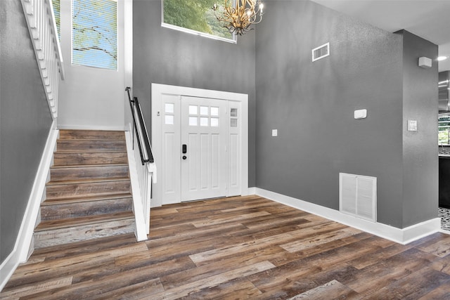 entryway featuring a towering ceiling, a chandelier, and dark hardwood / wood-style flooring