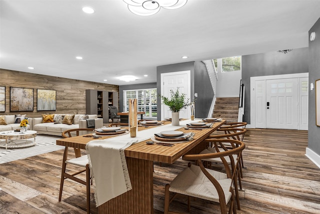 dining area with a healthy amount of sunlight, wood walls, and hardwood / wood-style flooring