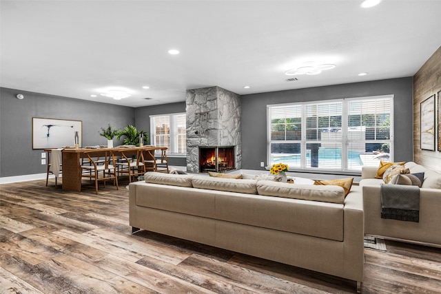 living room with hardwood / wood-style floors and a stone fireplace