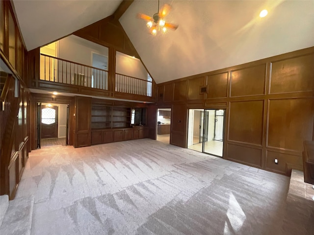 unfurnished living room with high vaulted ceiling, ceiling fan, and light colored carpet