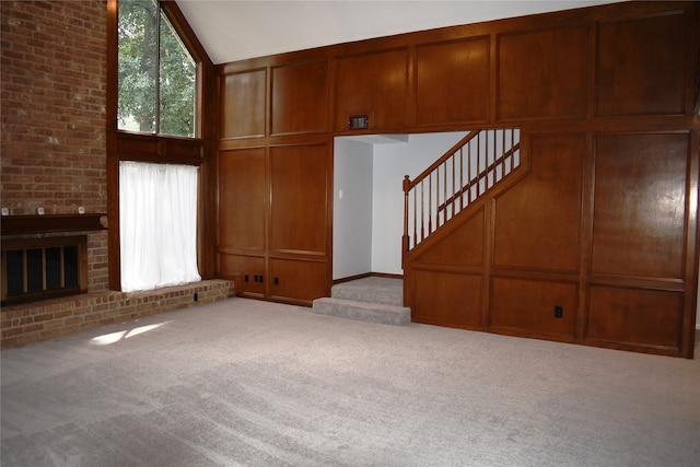 unfurnished living room with a fireplace, light colored carpet, and high vaulted ceiling