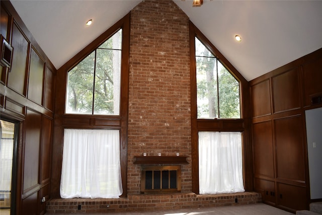 unfurnished living room with brick wall, a brick fireplace, and high vaulted ceiling