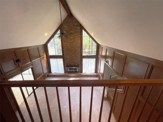 stairs with a brick fireplace, vaulted ceiling with beams, ceiling fan, and carpet floors