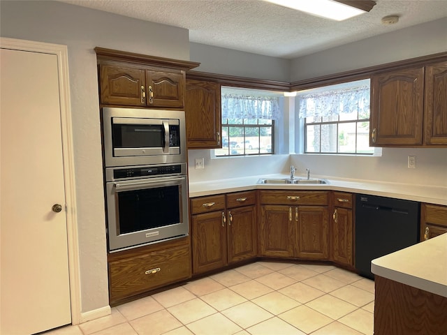 kitchen with a textured ceiling, appliances with stainless steel finishes, light tile patterned floors, and sink