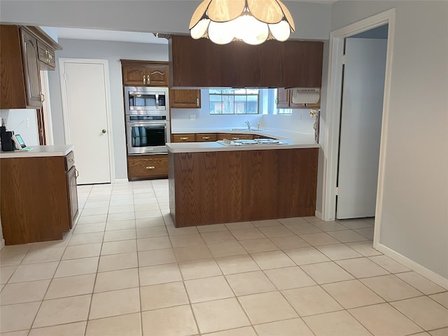 kitchen with kitchen peninsula, appliances with stainless steel finishes, light tile patterned floors, and sink