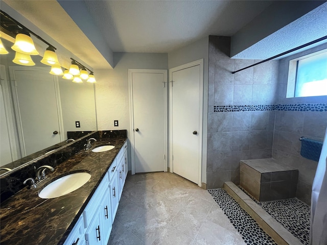 bathroom with vanity, a tile shower, and a textured ceiling