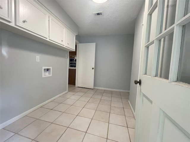 interior space with light tile patterned flooring, a textured ceiling, and white cabinetry