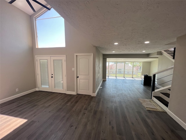 foyer entrance featuring a textured ceiling, ceiling fan, dark wood-type flooring, and high vaulted ceiling