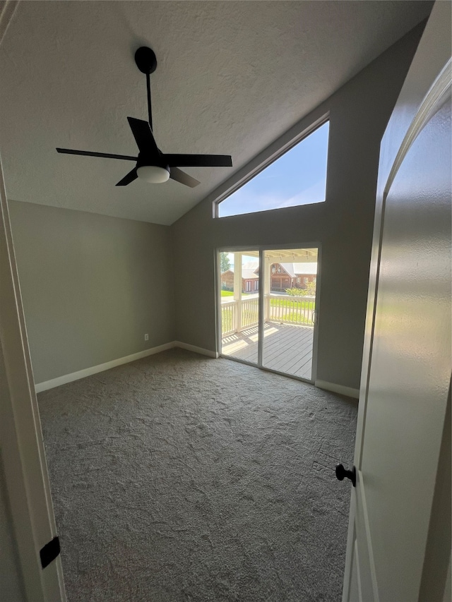 carpeted empty room with a textured ceiling, vaulted ceiling, and ceiling fan