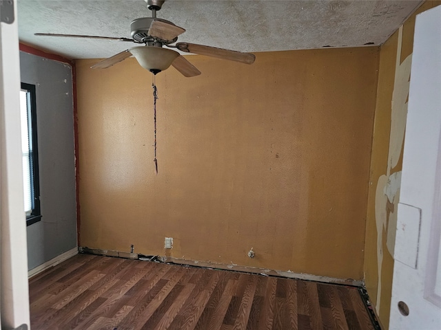 empty room with a textured ceiling, ceiling fan, and dark hardwood / wood-style flooring