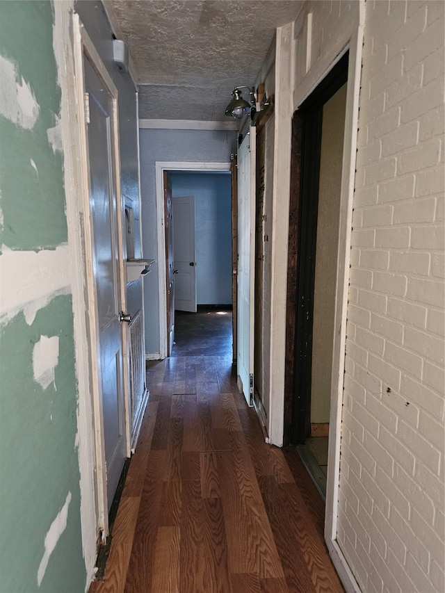 corridor featuring dark wood-type flooring and brick wall