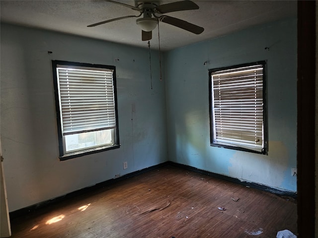 empty room with a textured ceiling, dark hardwood / wood-style floors, and ceiling fan