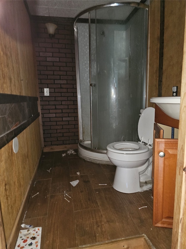 bathroom with a shower with shower door, vanity, tile patterned flooring, wooden walls, and toilet