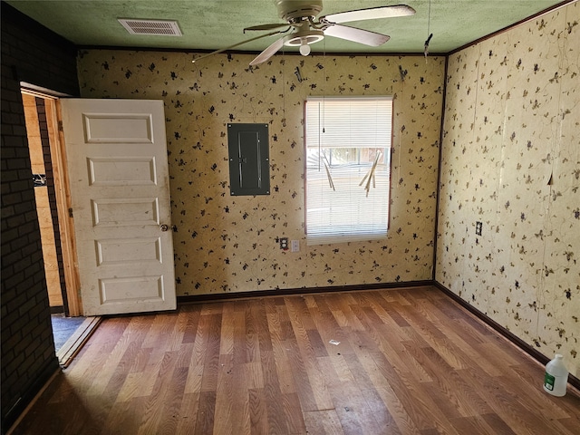 unfurnished room featuring ceiling fan, hardwood / wood-style flooring, electric panel, and a textured ceiling