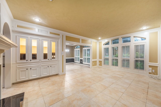 unfurnished living room with a textured ceiling, light tile patterned flooring, and ornamental molding