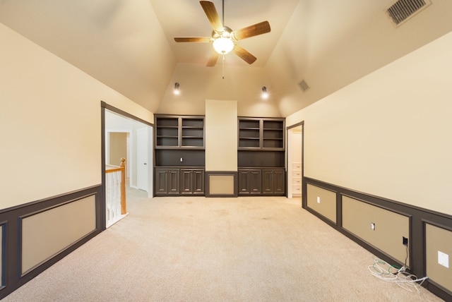 spare room featuring vaulted ceiling, light carpet, ceiling fan, and built in features