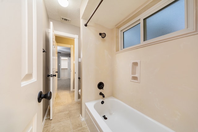 bathroom with a textured ceiling, shower / bathtub combination, toilet, and tile patterned floors