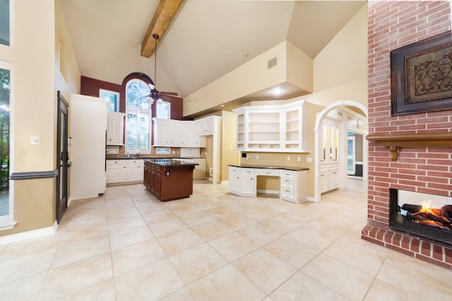 kitchen with ceiling fan, white cabinetry, high vaulted ceiling, and a kitchen island