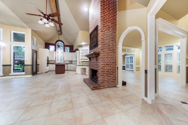 tiled living room with a fireplace, beam ceiling, ceiling fan, and high vaulted ceiling