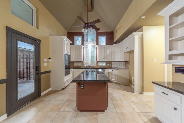 kitchen with ceiling fan, light tile patterned floors, high vaulted ceiling, white cabinetry, and a center island