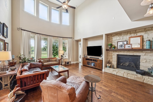 living room with high vaulted ceiling, wood-type flooring, ceiling fan, and a stone fireplace