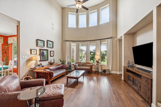 living room featuring ornamental molding, a towering ceiling, ceiling fan, and hardwood / wood-style flooring