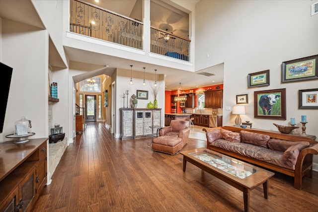 living room with a towering ceiling, a chandelier, and hardwood / wood-style floors