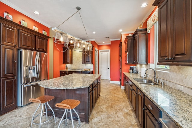 kitchen with ornamental molding, sink, stainless steel fridge with ice dispenser, a center island, and a breakfast bar area