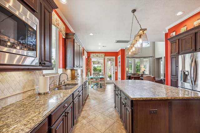 kitchen with appliances with stainless steel finishes, hanging light fixtures, a kitchen island, crown molding, and sink